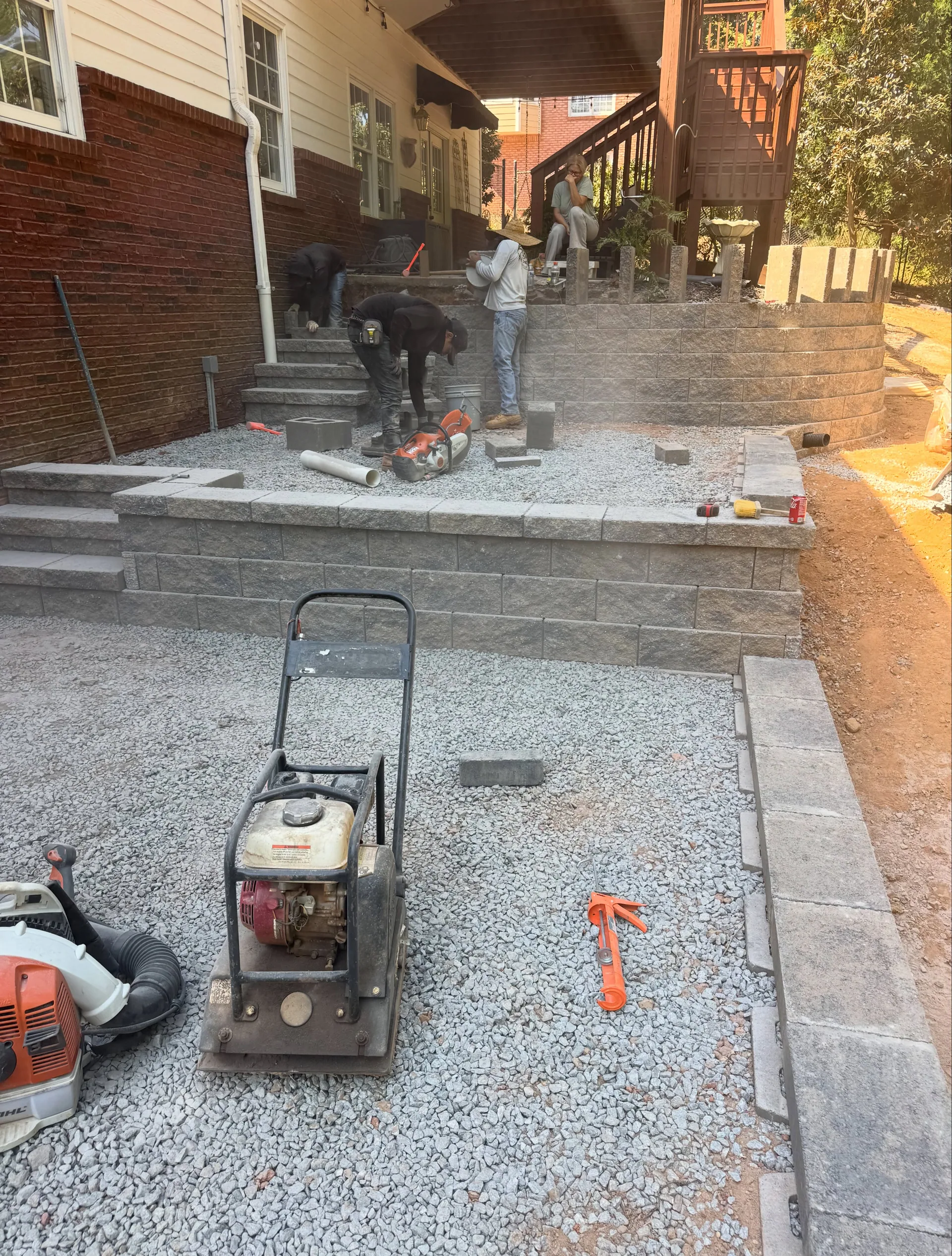 Plate compactor gravel base tiered block walls crew cutting pavers loganville